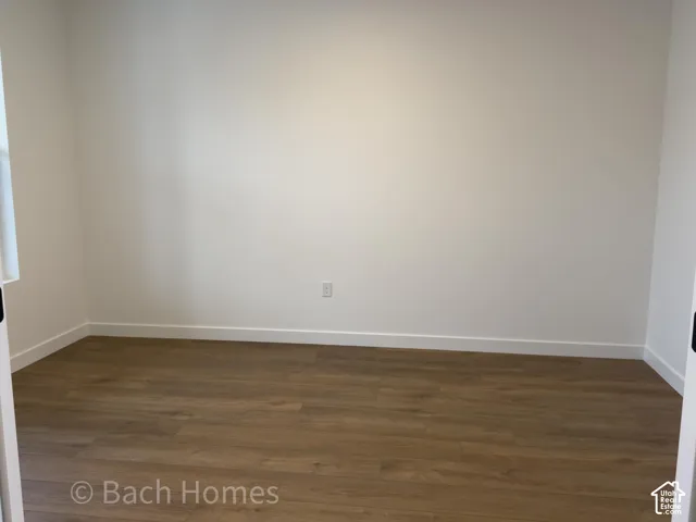 Neutral interior room featuring wood-finish flooring and solid wall surfaces
