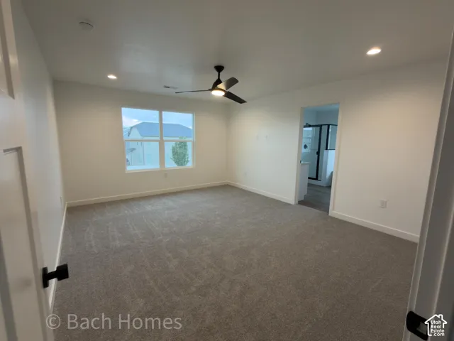Neutral-toned carpeting, recessed ceiling lighting, a matte black three-blade ceiling fan, and multi-pane windows