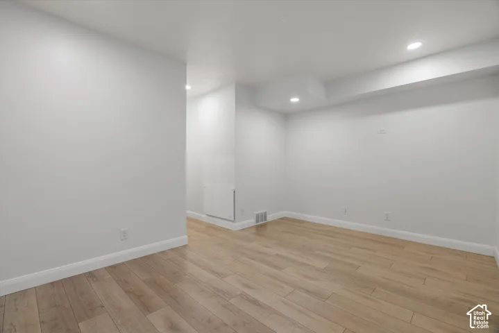 Spacious interior room featuring light wood-finish flooring, white baseboards, and neutral wall tones