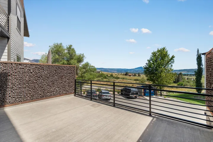 Spacious outdoor balcony featuring a concrete surface, contemporary horizontal metal railing, and a decorative gabion wall