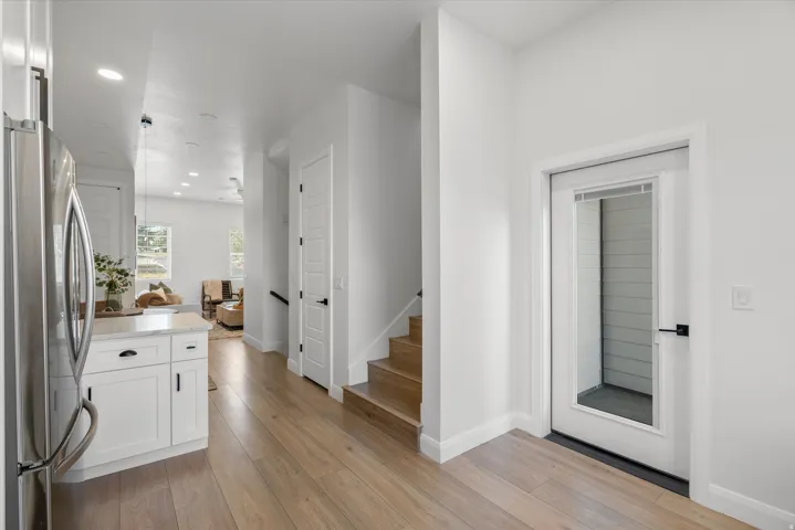Entryway featuring a glass-panel door, wood-finish flooring, and crisp white walls