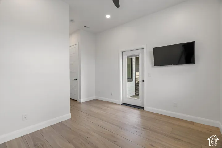 Light wood-finish flooring with white baseboards and walls