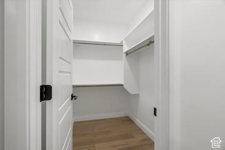 Walk-in closet featuring built-in shelving, hanging rods, and wood-finish flooring