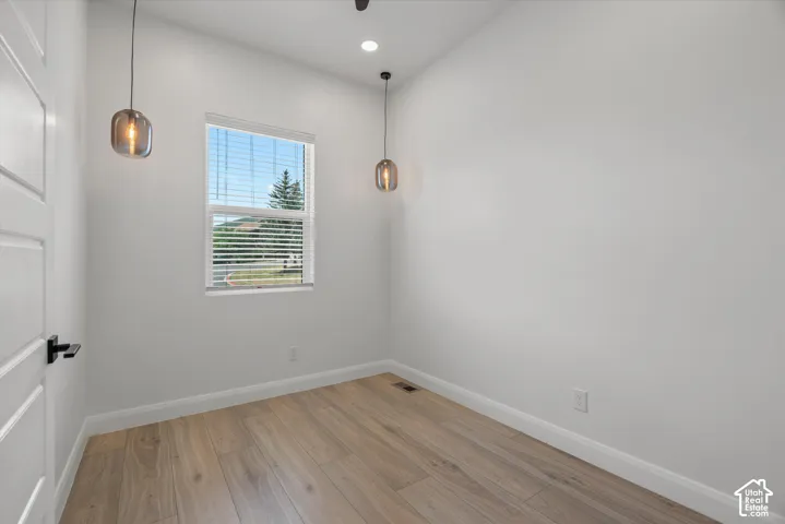 Room featuring wood-finish flooring, white baseboards, and a single window with blinds