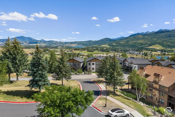 Residential development featuring modern architecture, extensive landscaping with mature trees, and a paved street