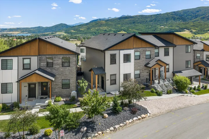 Contemporary townhome exterior featuring stone accents, horizontal siding, and wood-finish gables