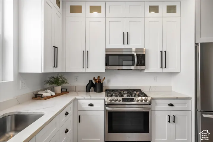 Contemporary kitchen featuring white shaker cabinetry, stainless steel appliances, marble-look countertops, and a stainless steel undermount sink