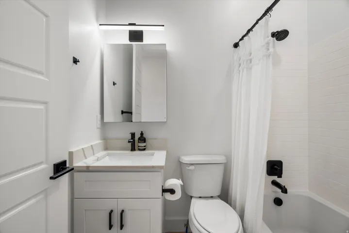 Bathroom featuring a white subway tile surround, matte black shower fixtures, and a curved shower rod