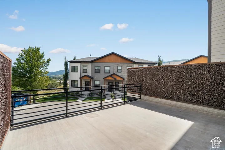 Spacious concrete patio featuring black metal railings and gabion walls