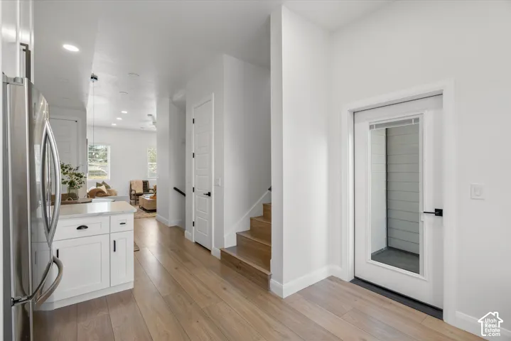 Entryway featuring a glass-panel door, wood-finish flooring, and crisp white walls