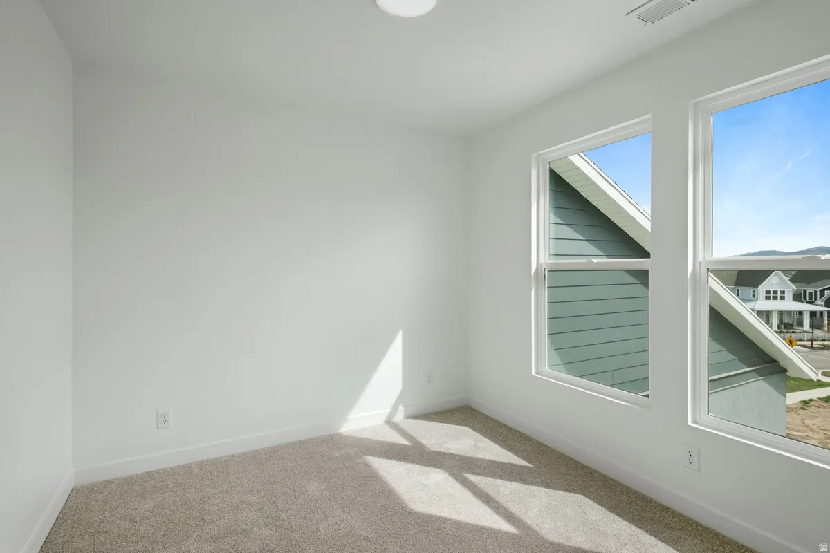 Bright room featuring two large windows, neutral carpeting, white baseboards, and a flush-mount ceiling light