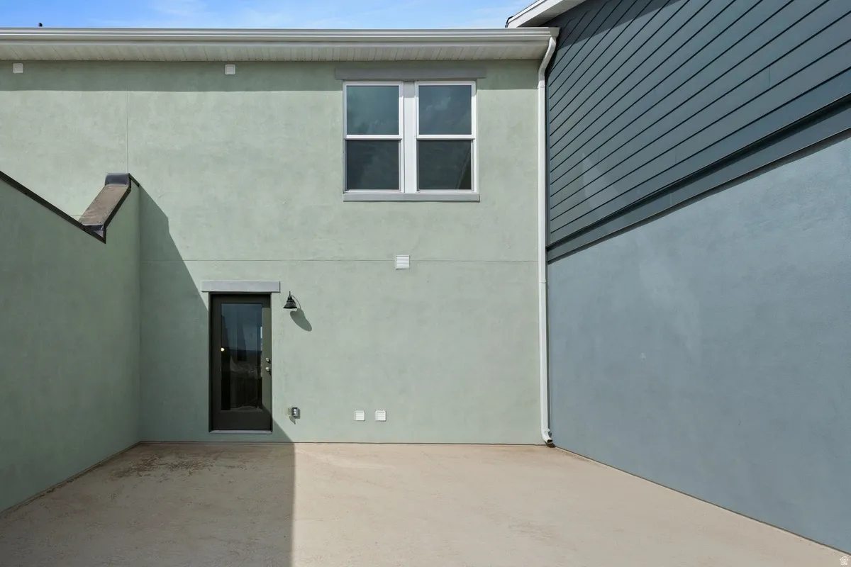 Exterior patio space featuring a concrete slab, stucco siding, and a rear entry door