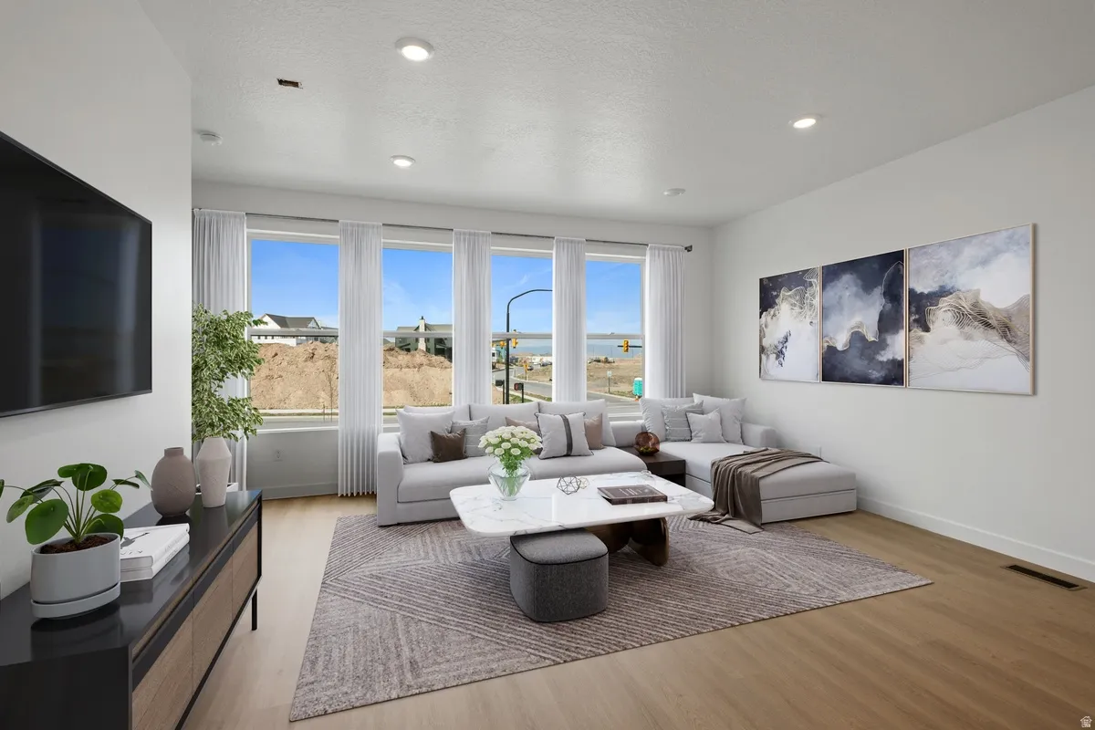 Open-concept living space with expansive windows, light wood-finish flooring, recessed lighting, and a neutral color palette