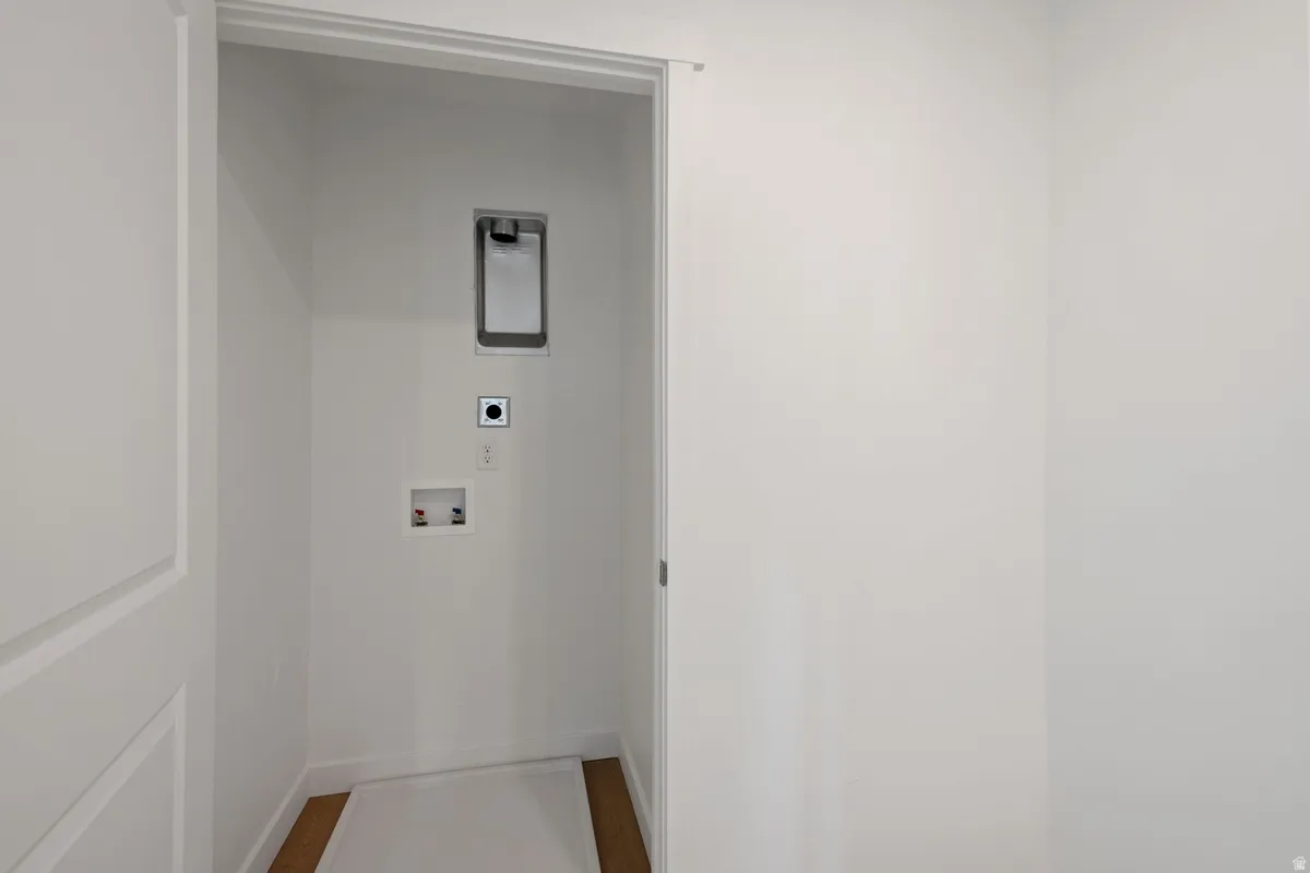 Dedicated laundry area with hookups for appliances, featuring white walls, white trim, and wood-finish flooring