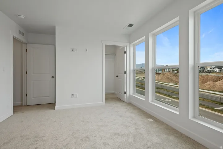 Room featuring three large windows, white trim, and light-toned carpeting