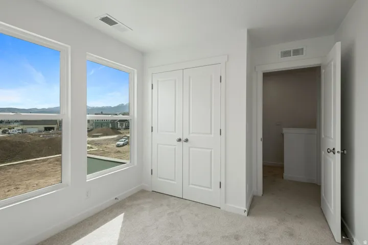 Room featuring two large windows, white walls, and light-colored carpet flooring