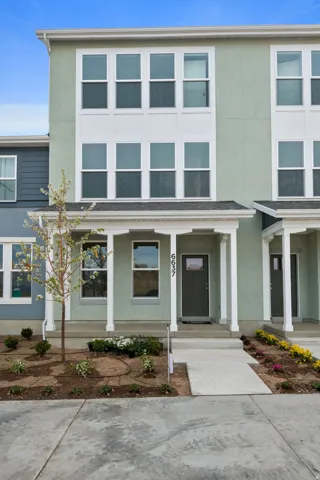 Contemporary townhome exterior featuring a light green stucco facade and white trim accents