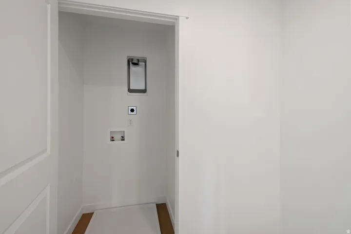 Dedicated laundry area with hookups for appliances, featuring white walls, white trim, and wood-finish flooring