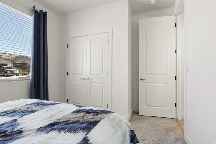 Bedroom featuring a double-pane window with blinds, white trim, and light gray carpeting