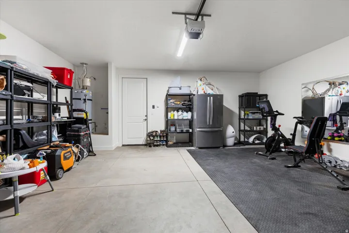 Spacious garage featuring concrete flooring, a white interior door, and overhead lighting