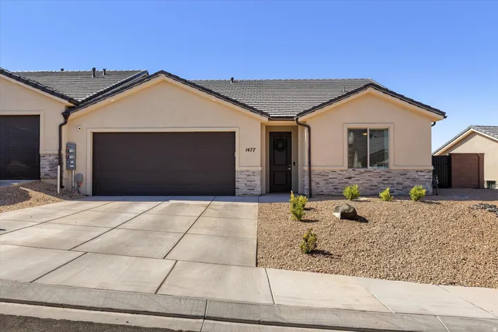 Stucco exterior with stone veneer accents and a dark tile roof