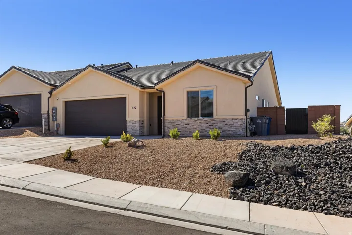 Single-story stucco exterior featuring stone veneer accents and a dark tile roof