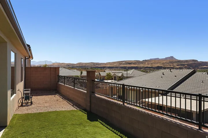 Private backyard featuring a partial artificial turf lawn, a gravel area, and a block wall with metal fencing
