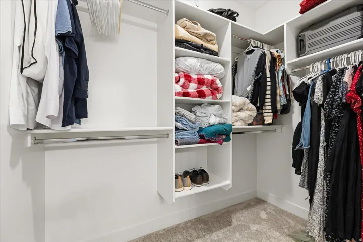 Custom closet system featuring white shelving, multiple hanging rods, and integrated storage compartments