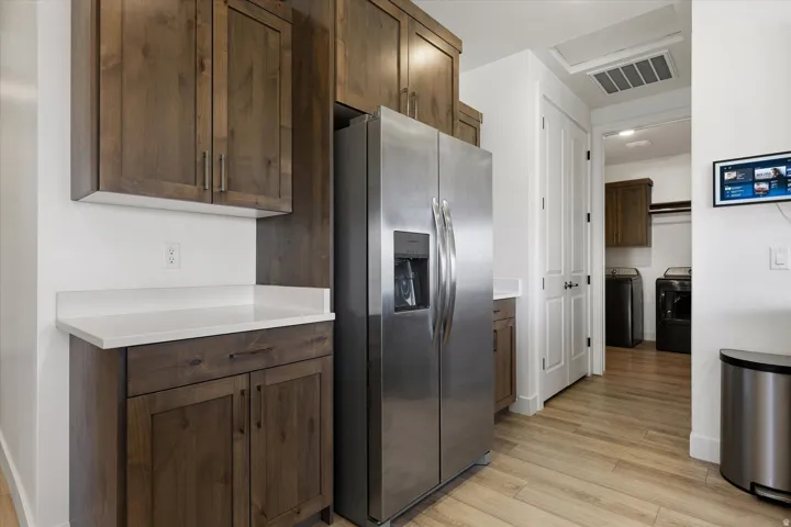 Stainless steel refrigerator with a water and ice dispenser, surrounded by wood-finish cabinetry and white countertops