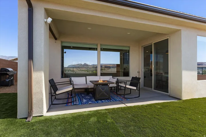 Covered patio featuring an artificial turf lawn, sliding glass doors, and expansive windows