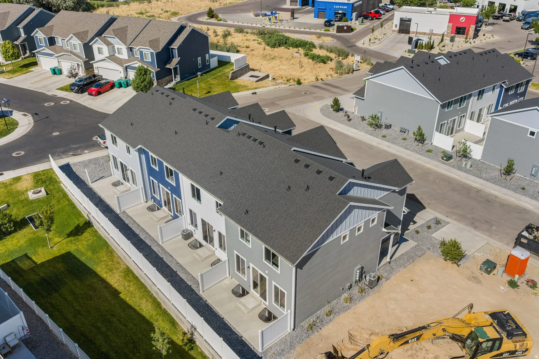 Row of townhomes featuring contrasting light and dark siding, private patios with privacy partitions, and dark shingle roofing