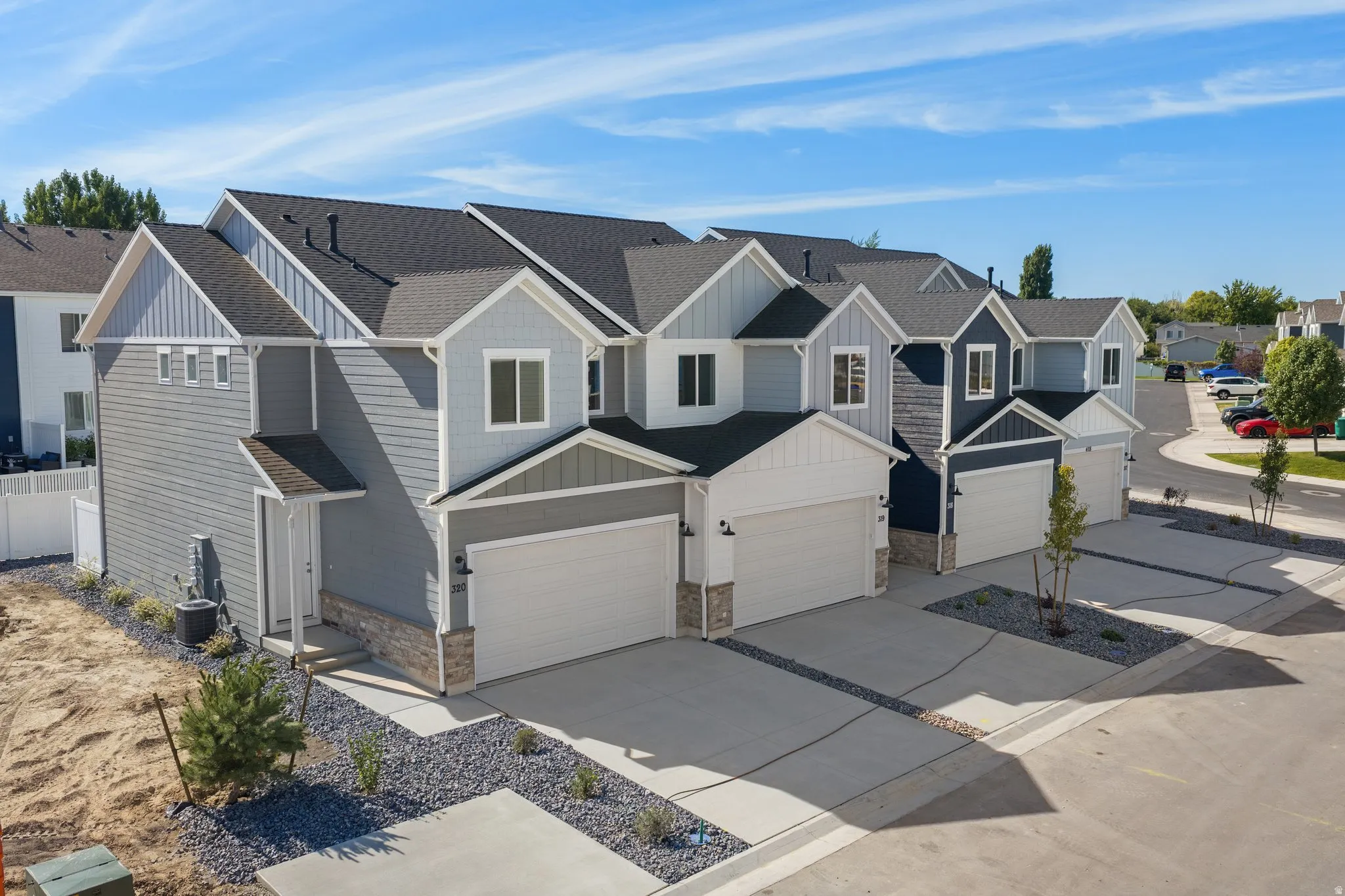Modern townhome-style residences featuring distinct exterior siding, gabled rooflines, and attached garages