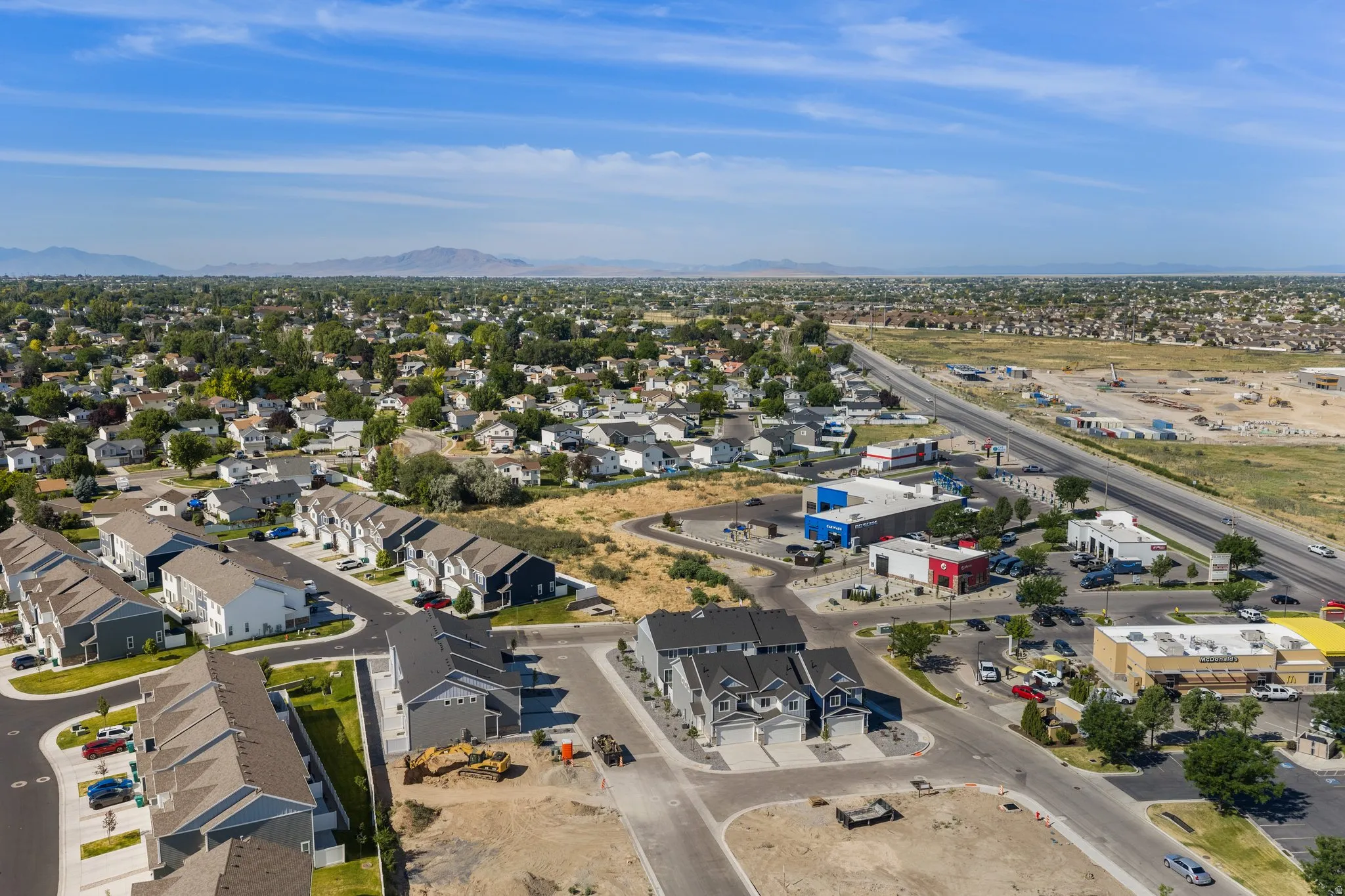 Aerial perspective showcasing a residential development alongside commercial buildings and a major roadway