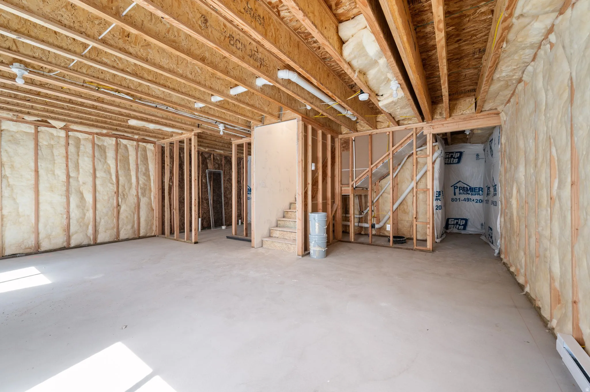Unfinished basement featuring exposed wood framing, concrete flooring, and insulated walls