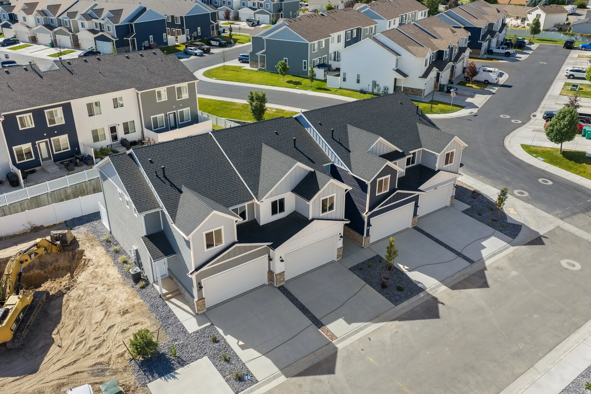 Modern townhome architecture featuring dark shingle roofing, light gray siding, white trim, and a two-car garage