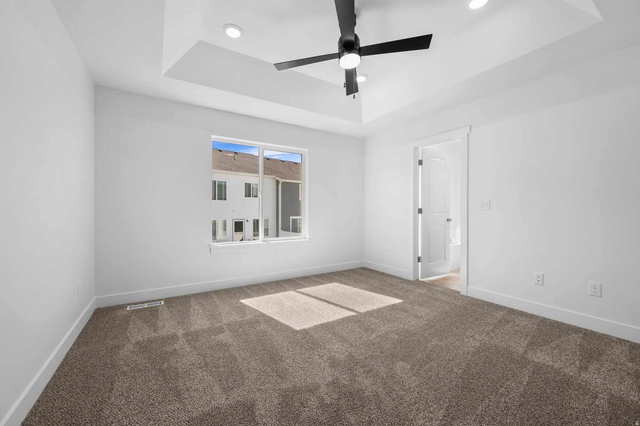 Carpeted bedroom with a tray ceiling and recessed lighting