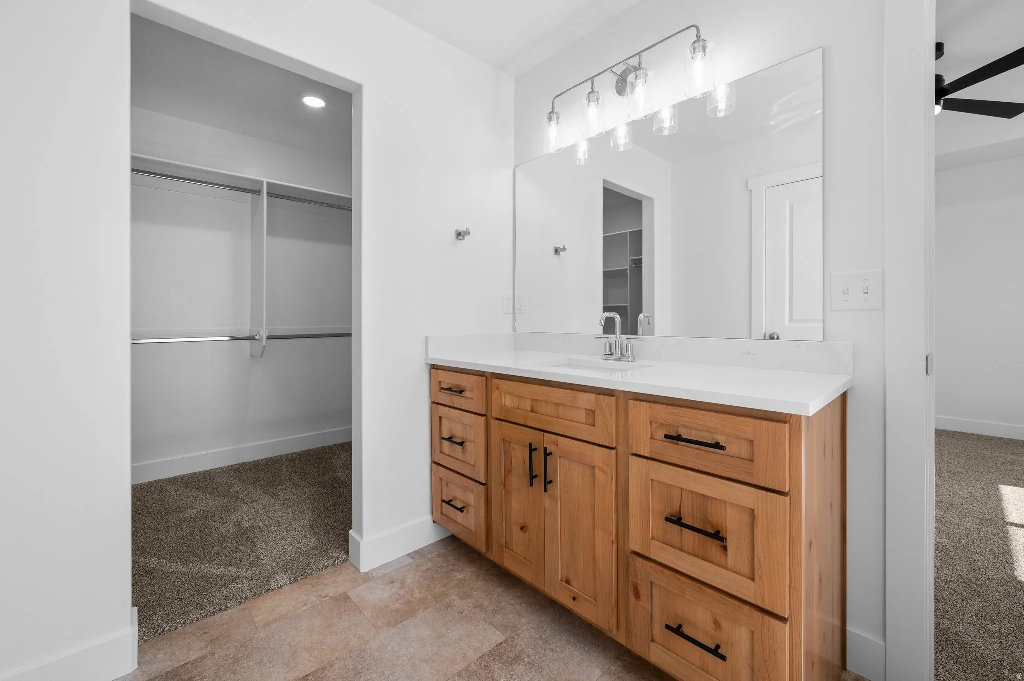 Single vanity with light wood-finish cabinetry, white countertop, and rectangular mirror