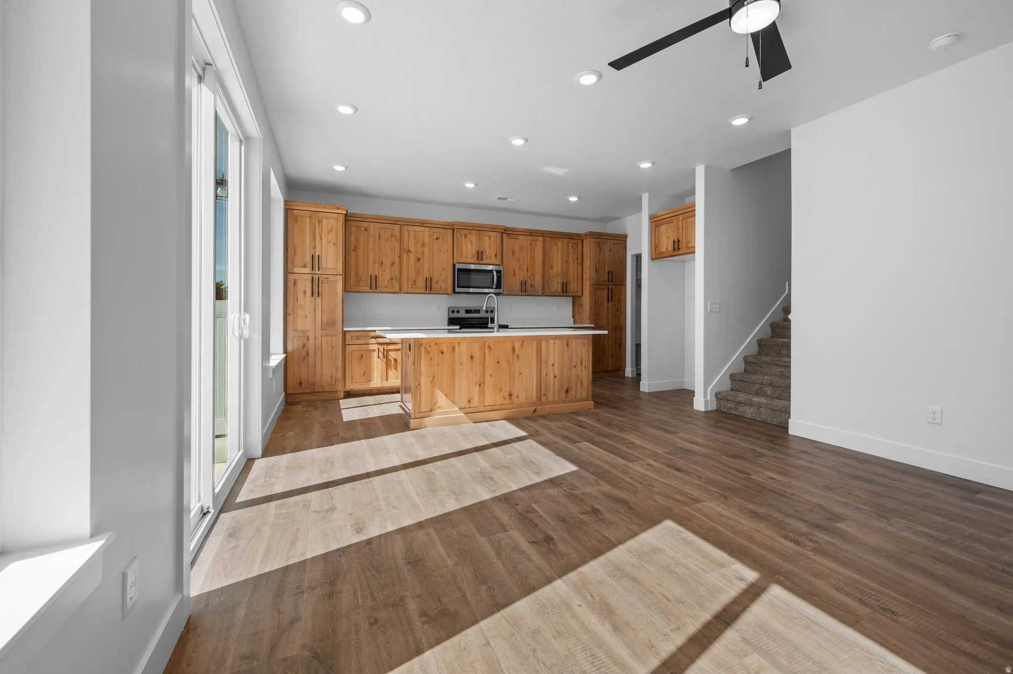 Open-concept living space featuring wood-finish flooring, recessed lighting, and a contemporary ceiling fan