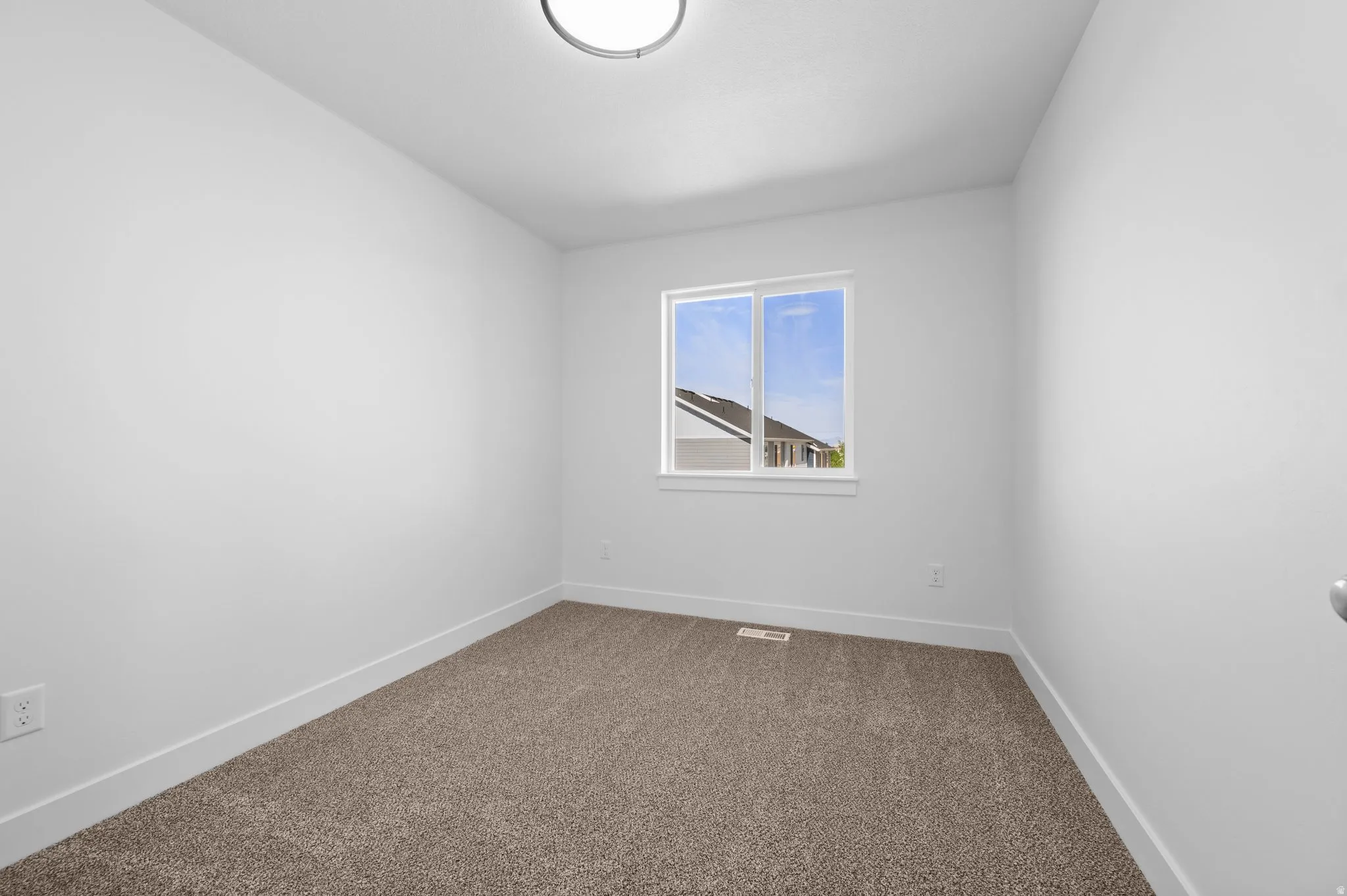 Carpeted room featuring white walls, a single window, and a flush-mount ceiling light