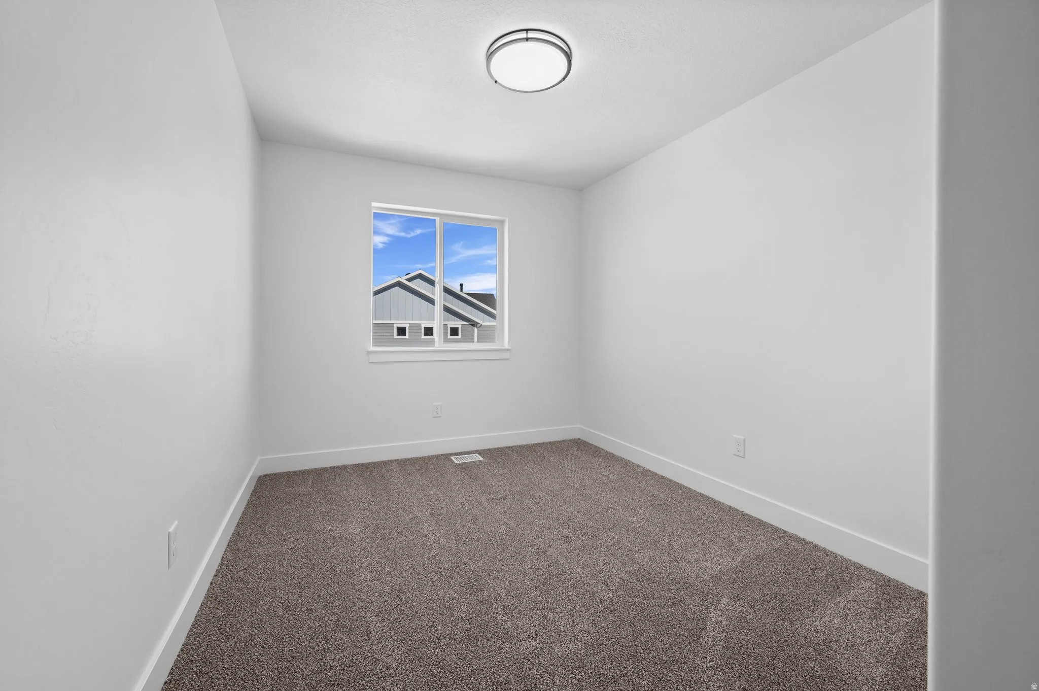 Neutral-toned room featuring a window with white trim, gray carpet, and white baseboards