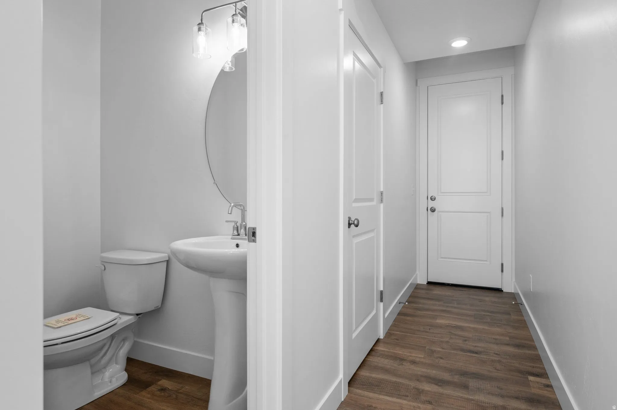 Powder room featuring a pedestal sink, oval mirror, and contemporary vanity light fixture