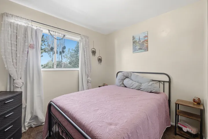 Bedroom featuring a large window, neutral wall paint, and dark-toned flooring