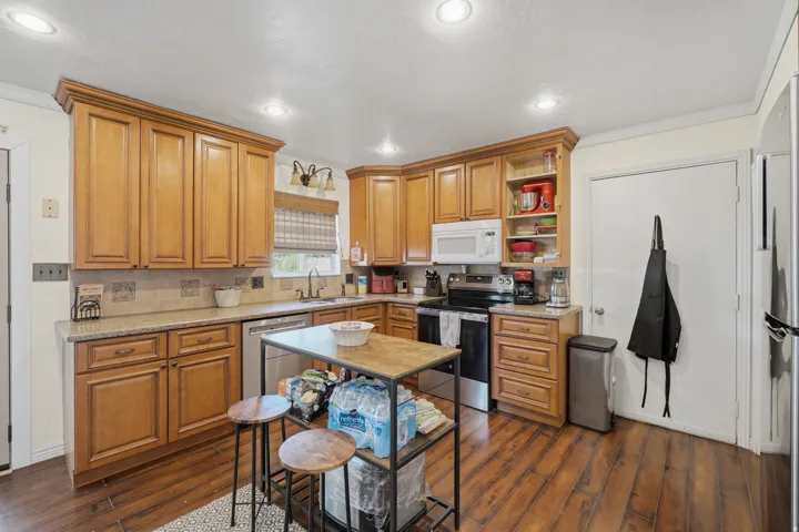 Kitchen featuring wood-finish flooring, recessed lighting, wood cabinetry, granite countertops, and a tile backsplash