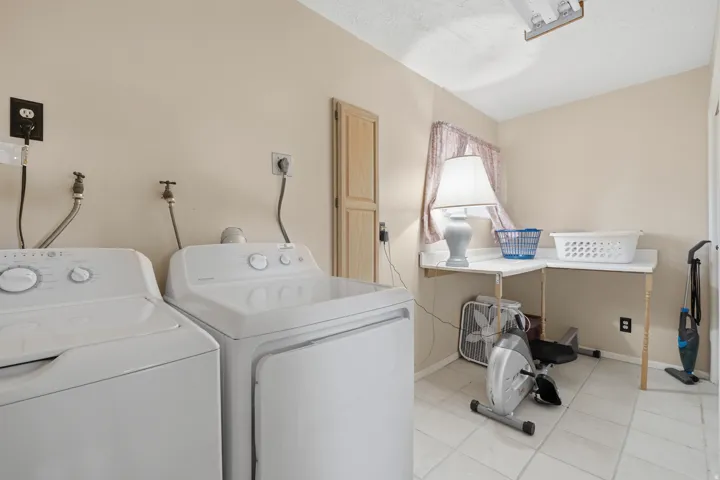 Laundry area featuring light-toned wall paint and square floor tiles