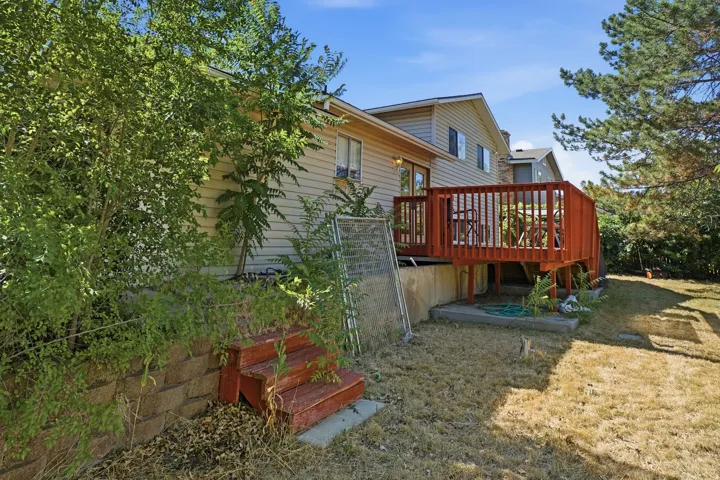 Rear exterior featuring a raised wooden deck with railings, sliding glass door access, and light-colored siding