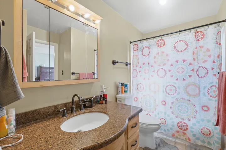 Bathroom featuring a curved vanity with a granite-finish countertop and an undermount sink