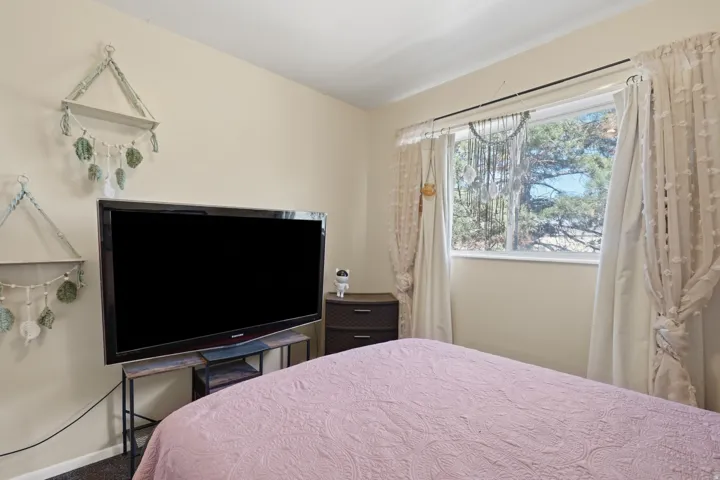 Bedroom featuring a single window, neutral wall paint, and dark carpet flooring