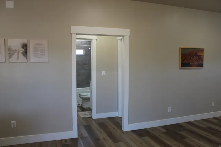 Interior doorway opening to a bathroom featuring a white tub, toilet, and tiled shower surround with a window