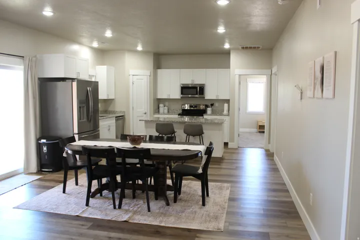 Open-concept kitchen and dining area featuring wood-finish flooring, recessed lighting, white cabinetry, and stainless steel appliances