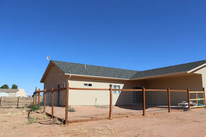 Exterior featuring a tan stucco finish and a dark shingle roof
